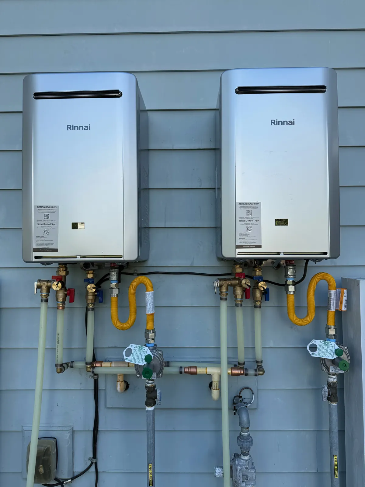 Two Rinnai tankless water heaters mounted on an exterior wall